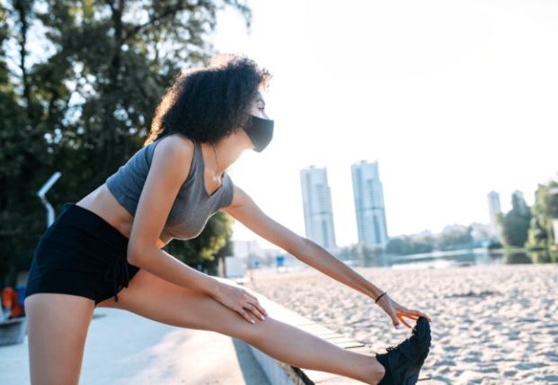 A woman stretching her legs on the beach.