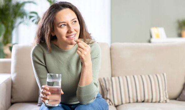 A woman sitting on the couch with a glass of water.